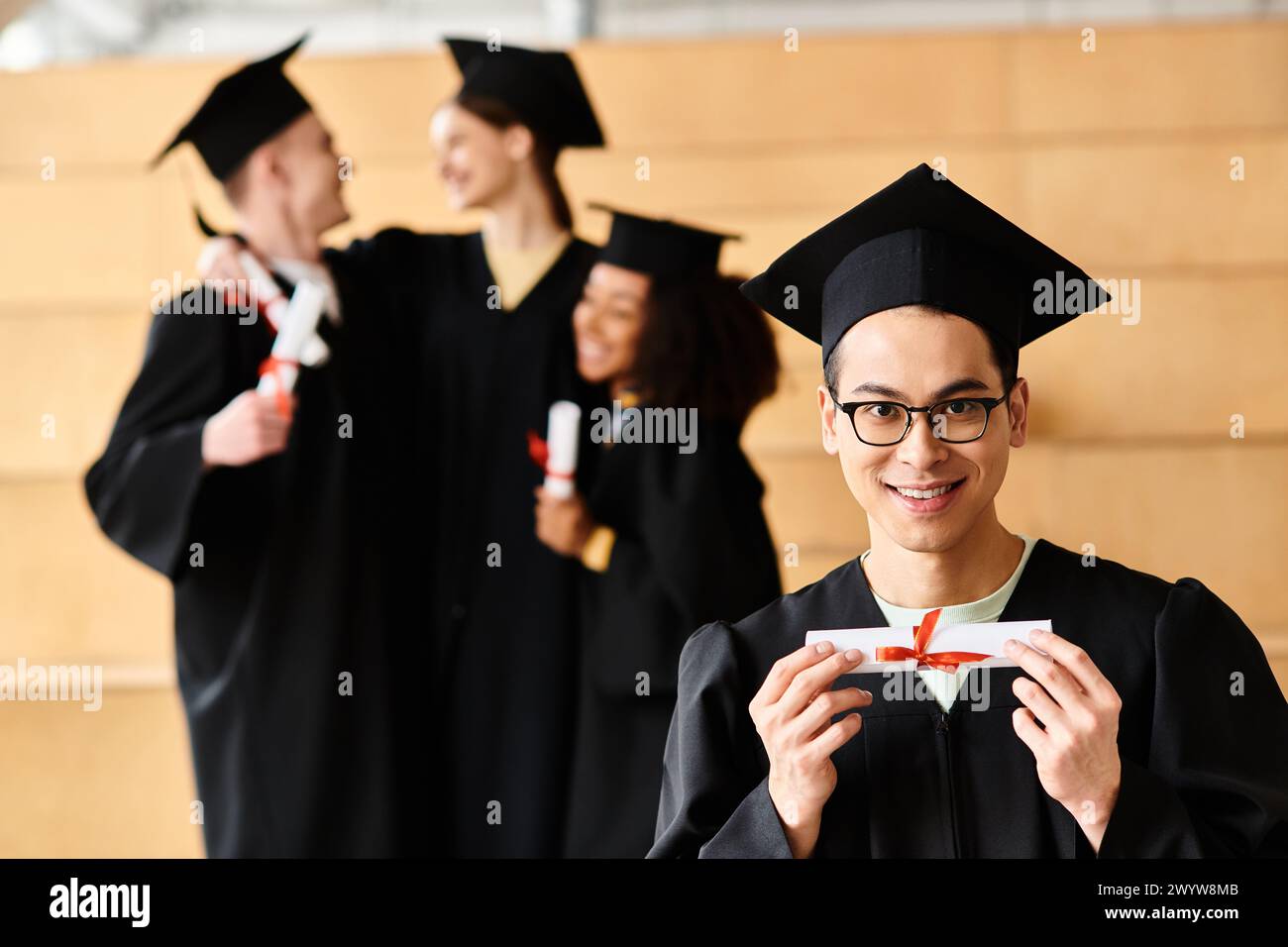 Ein vielseitiger Mann in einem Abschlusskleid hält triumphierend ein Diplom. Stockfoto
