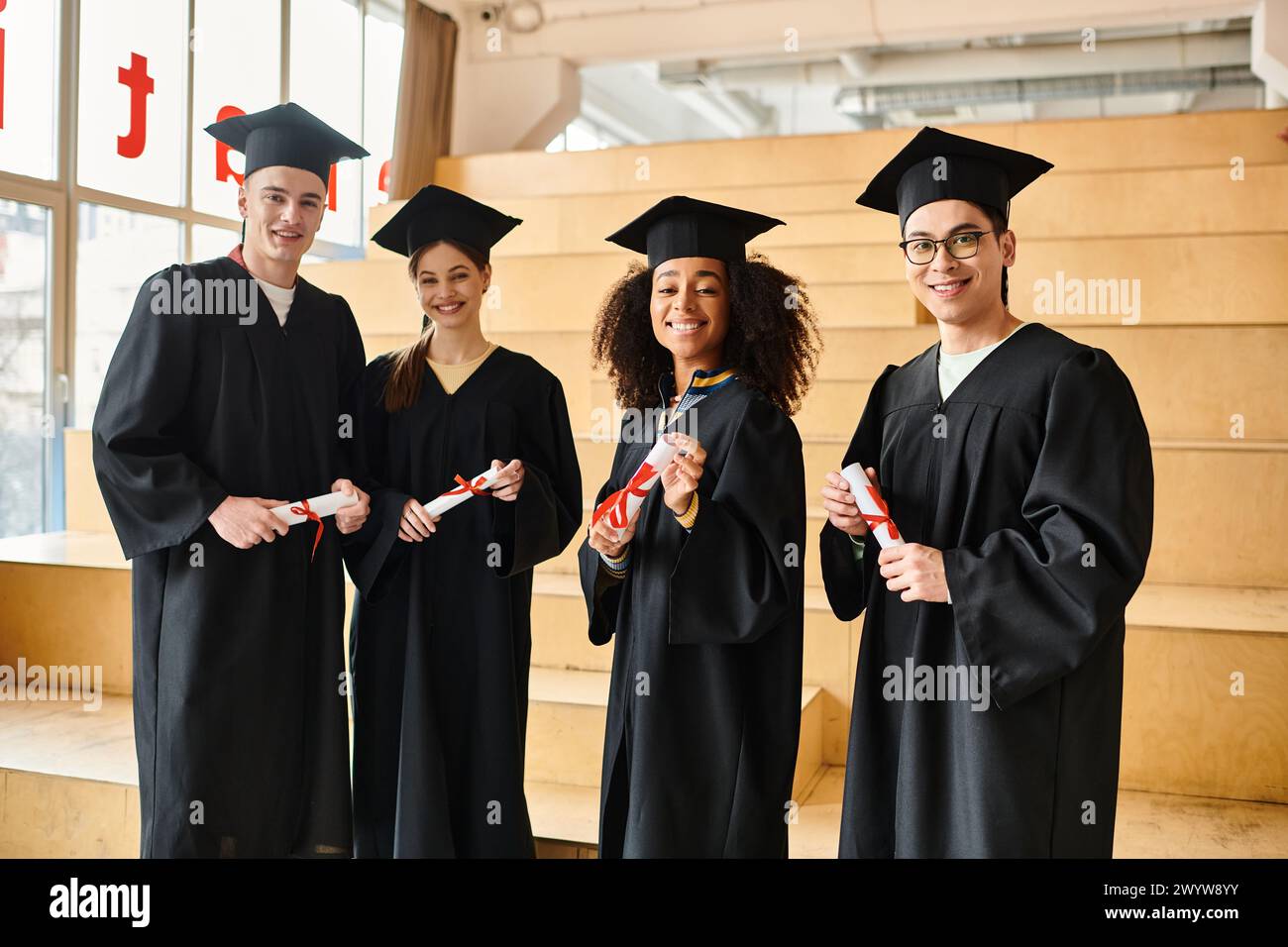 Verschiedene Gruppen von Studenten in Abschlusskleidern, die mit akademischen Kappen und Diplomen posieren Stockfoto