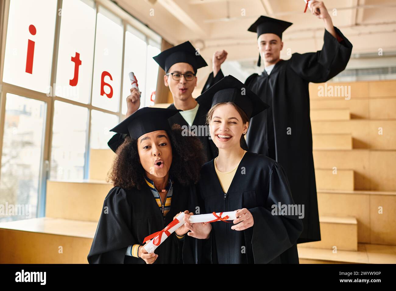 Multikulturelle Studenten in Abschlusskleidern und -Mützen posieren nach Abschluss ihrer akademischen Reise gerne für ein Foto. Stockfoto