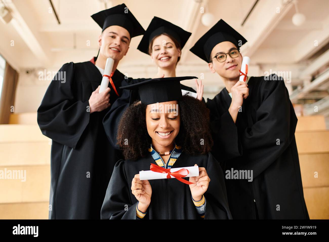 Verschiedene Gruppen fröhlicher Studenten in Abschlusskleidern und -Mützen posieren für ein festliches Bild im Haus. Stockfoto