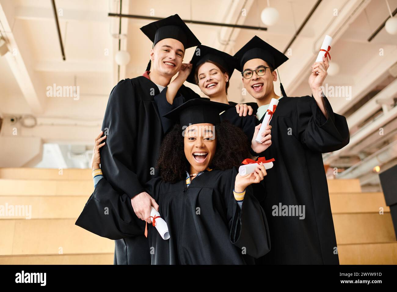 Eine vielfältige Gruppe von Studenten in Abschlusskleidern posiert mit akademischen Kappen für ein unvergessliches Bild ihrer Leistung. Stockfoto