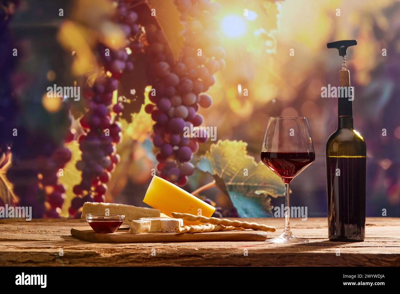 Fesselndes Bild, das die Essenz der Weinherstellung mit einer Flasche Wein und einem Glas Rotwein, Käse vor dem Hintergrund malerischer Trauben festmacht Stockfoto