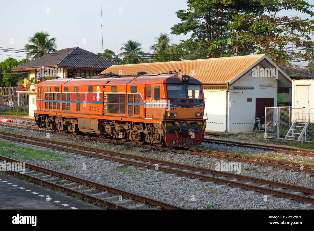 CHA AM, THAILAND - 13. DEZEMBER 2018: Orange-Diesellokomotive auf einem Bahnhofsgleis an einem sonnigen Abend Stockfoto