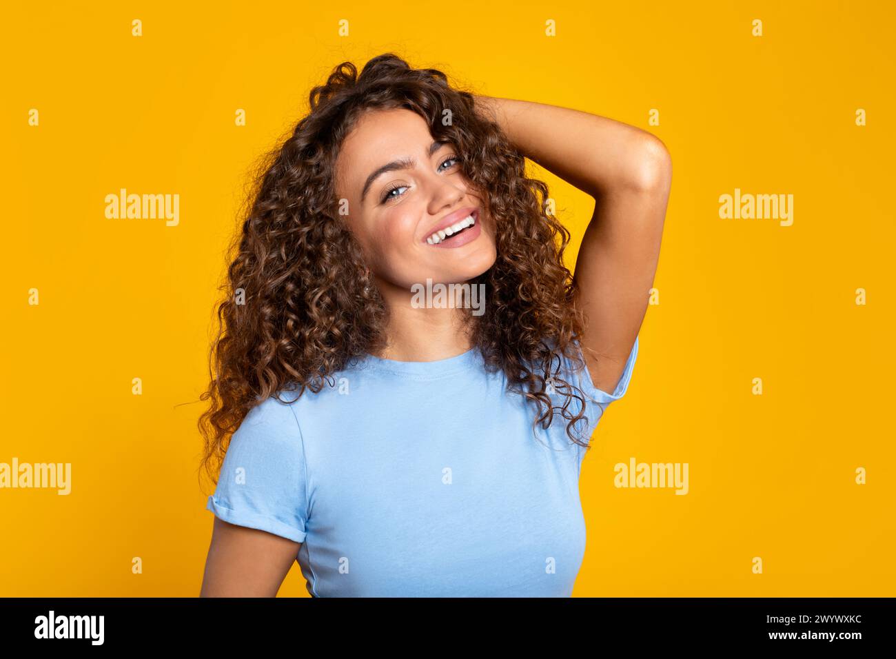 Entzückte junge Frau, die hell auf Gelb lächelt Stockfoto