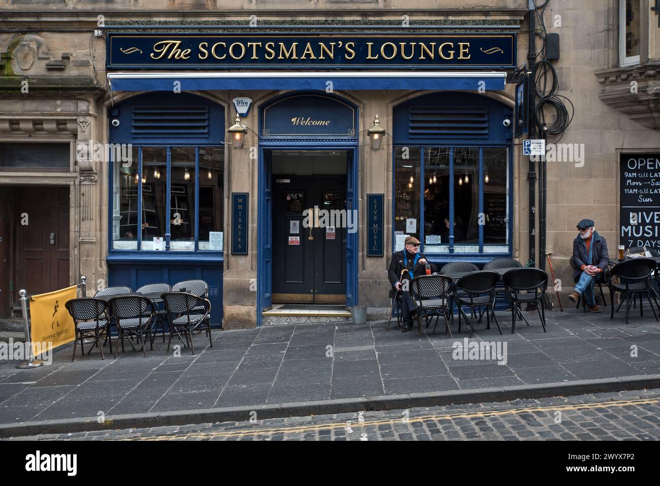 Zwei ältere Männer sitzen vor der Scotsman's Lounge in der Cockburn Street in Edinburghs Altstadt. Stockfoto