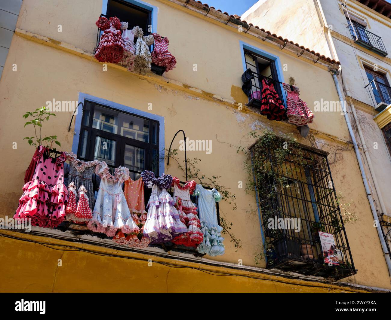 Traditionelle Flamenco-Kostüme hängen an der Balkonfassade des spanischen andalusischen Hauses in Málaga, Spanien. Stockfoto