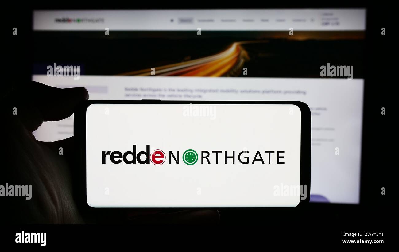 Person, die ein Mobiltelefon mit dem Logo der britischen Autovermietung Redde Northgate plc vor der Business-Website hält. Schwerpunkt auf dem Display des Telefons. Stockfoto