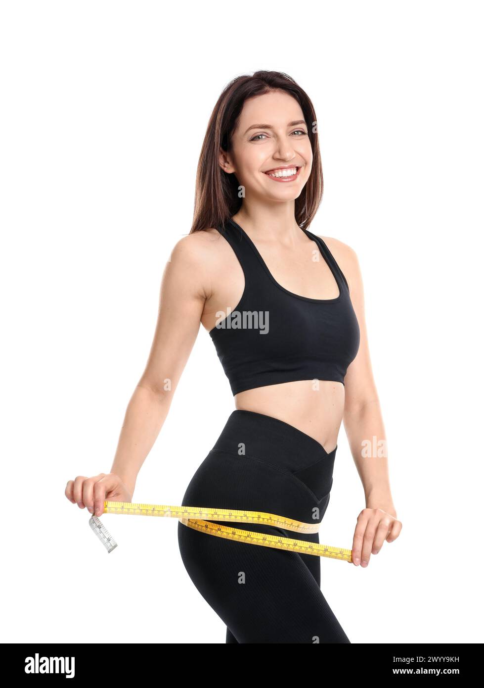 Glückliche junge Frau mit Maßband, das ihren schlanken Körper vor weißem Hintergrund zeigt Stockfoto