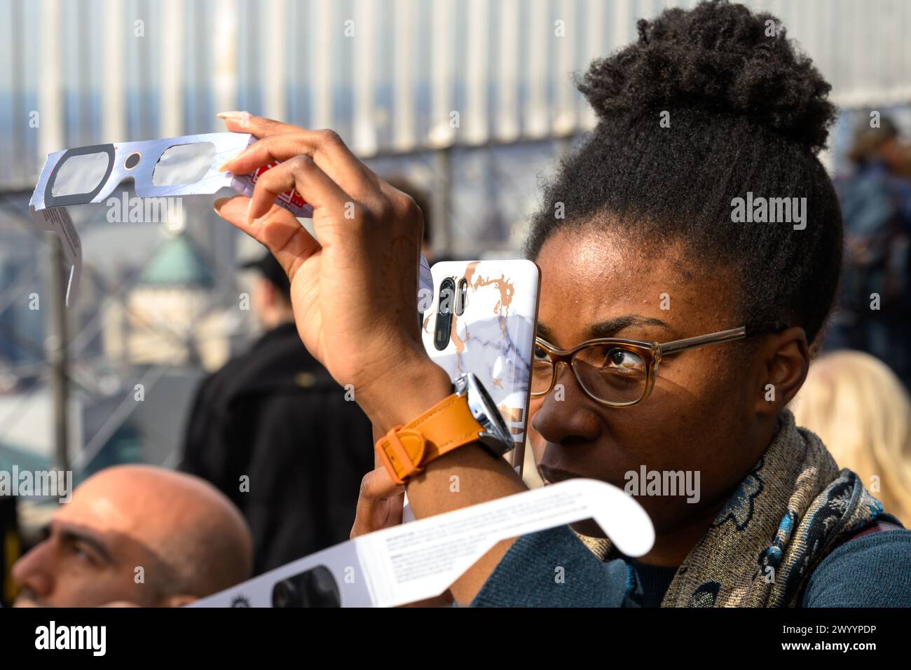 New York, USA. April 2024. Eine Frau fotografiert eine Sonnenfinsternis von der Aussichtsplattform des Empire State Building mit einer speziellen Brille am Telefon. Credit: Alamy Live News/Enrique Shore Credit: Enrique Shore/Alamy Live News Stockfoto