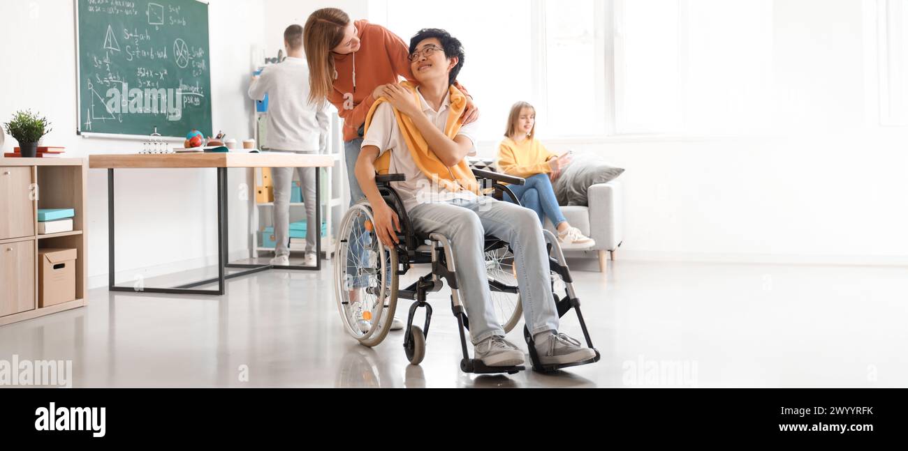 Teenager-Mädchen mit ihrer Klassenkameradin im Rollstuhl in der Schule Stockfoto