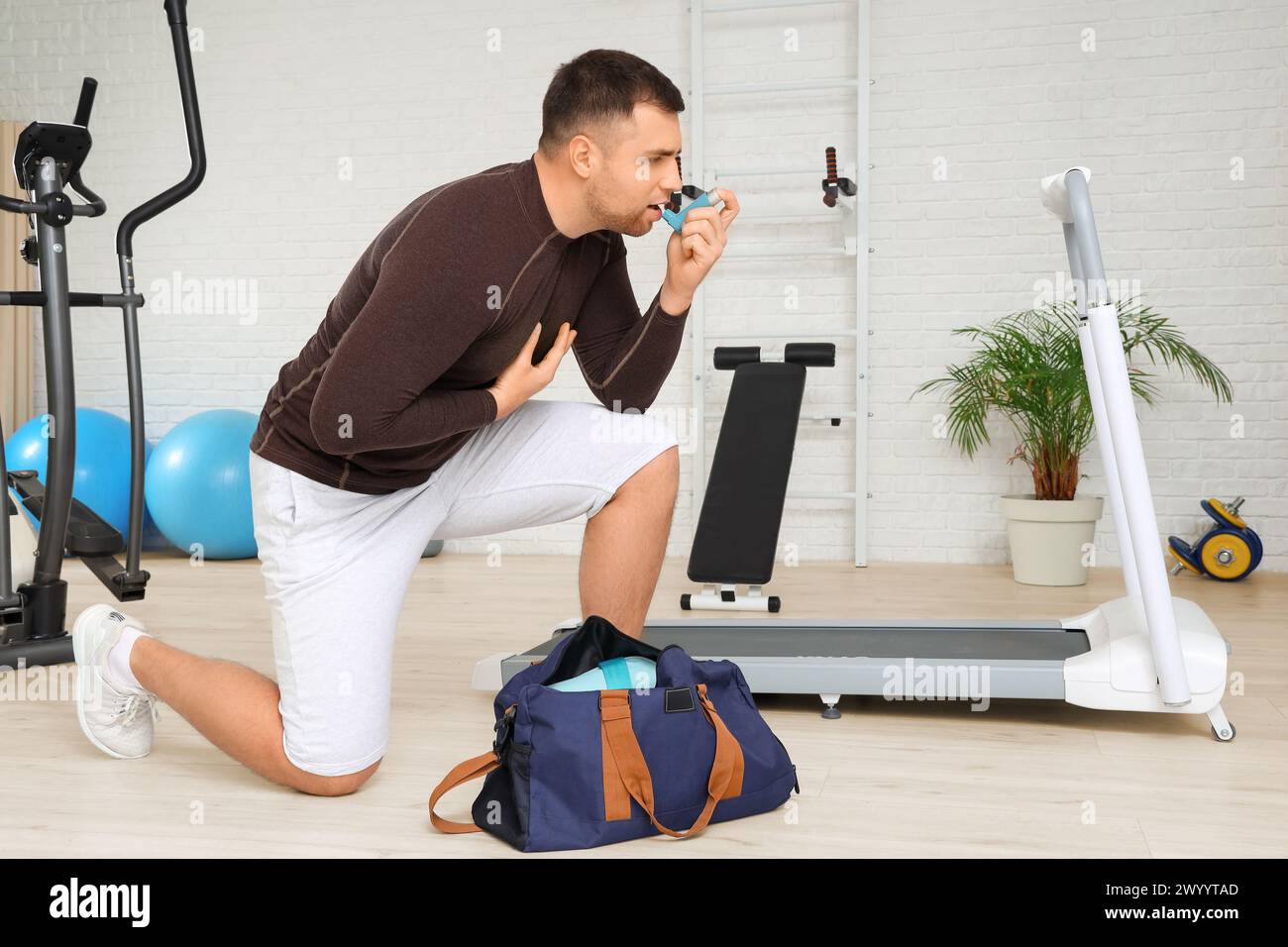 Sportlicher junger Mann mit Tasche mit Inhalator im Fitnessstudio Stockfoto