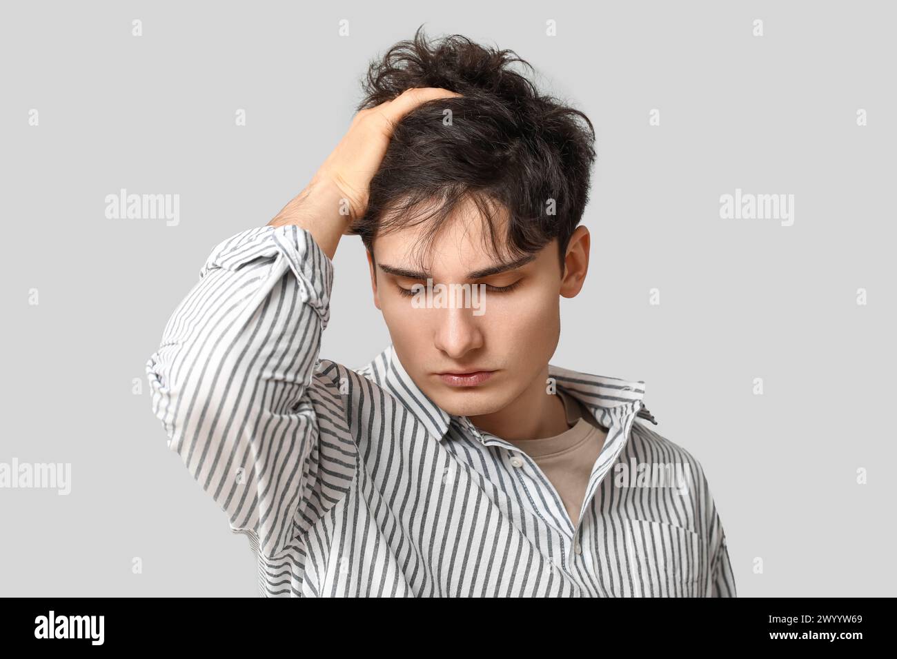 Junger dunkelhaariger Mann auf grauem Hintergrund Stockfoto