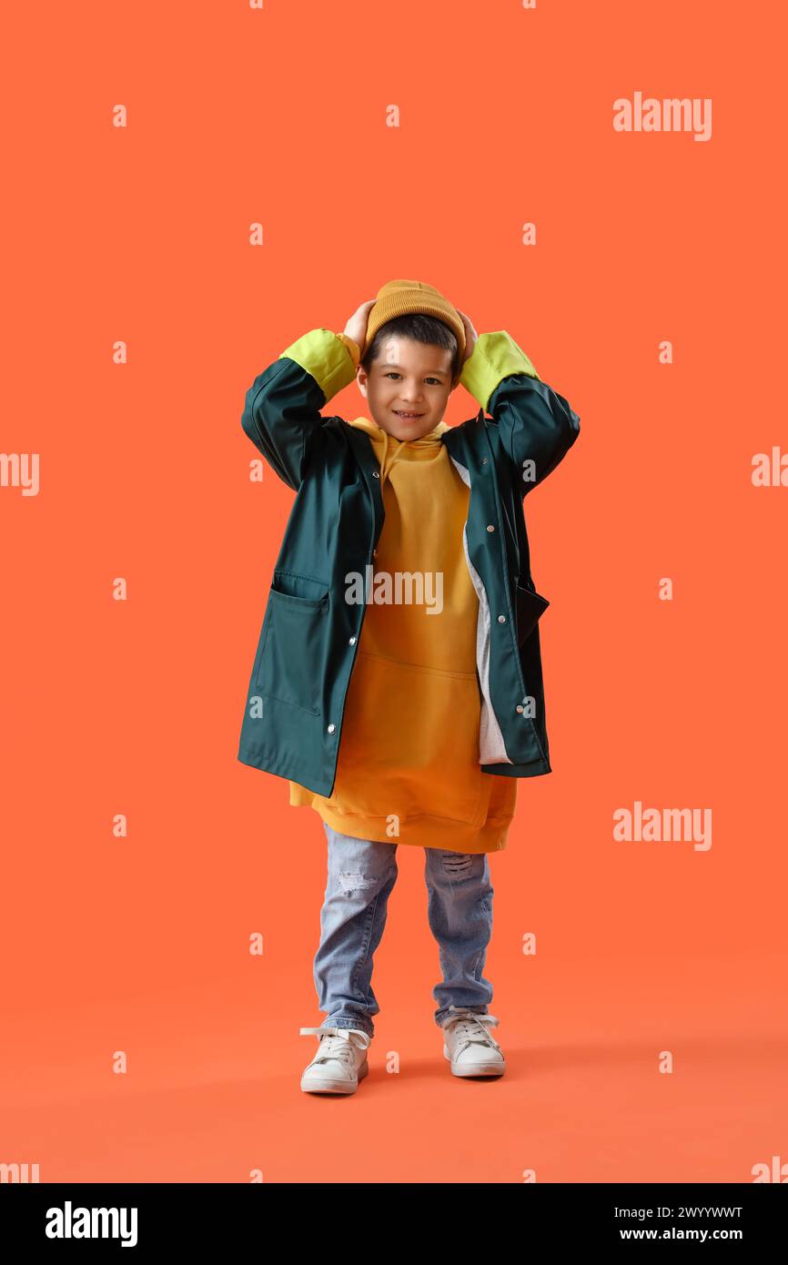 Süßer kleiner asiatischer Junge in Erwachsenenkleidung auf orangem Hintergrund Stockfoto