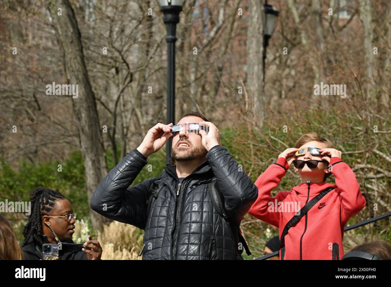 8. April 2024, %G: (NEU) die Sonnenfinsternis 2024 in New York City. April 2024, New York City, New York, USA. Die lang erwartete Sonnenfinsternis wird erscheinen, wenn der Mond die Sonnenstrahlen blockiert, während er zwischen Sonne und Erde vorbeizieht und einen Schatten auf die Erde wirft. Um 14:00 Uhr wurde die Sonnenfinsternis von einer großen Menge von Menschen jeden Alters begrüßt. Diese Menschenmenge erstreckte sich vom Winter Garden Atrium (wo ich stand) auf der Westseite von Manhattan, neben dem Hudson River, hinunter zur South Ferry. Die Sonnenfinsternis endete um 16:36 Uhr Eastern Time. Die nächste Sonnenfinsternis in New York wird im y sein Stockfoto