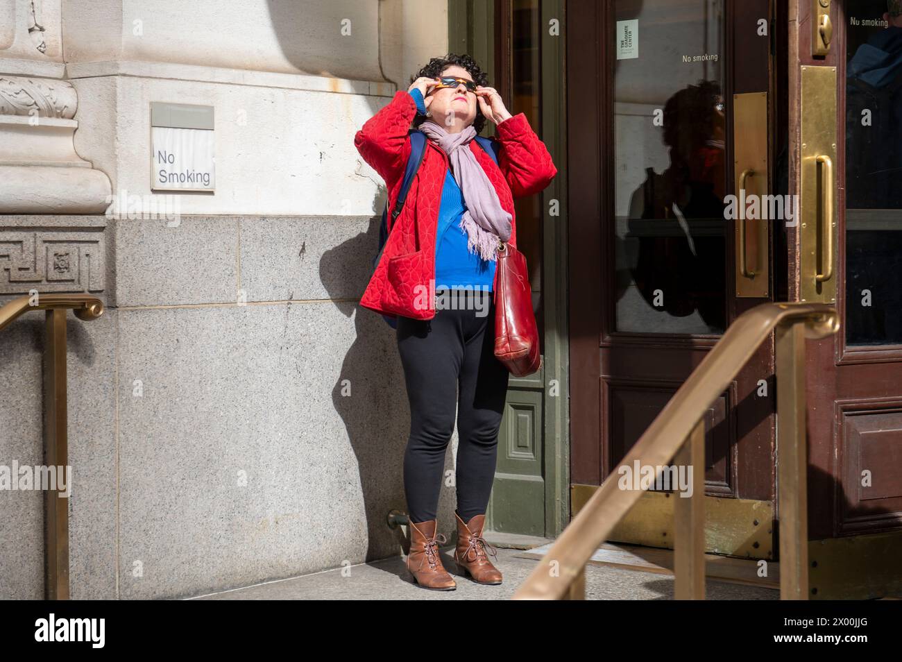 NEW YORK, NEW YORK - 8. APRIL 2024: Die Menschen beobachten eine teilweise Sonnenfinsternis auf der 5th Avenue in New York City. Mit der ersten Sonnenfinsternis, die seit sieben Jahren Nordamerika durchquerte, war New York City nicht auf dem Weg der Totalität, da nur 90 % der Sonne vom Mond bedeckt waren; die nächste Sonnenfinsternis, die in den Vereinigten Staaten zu sehen ist, wird 2044 sein. Stockfoto