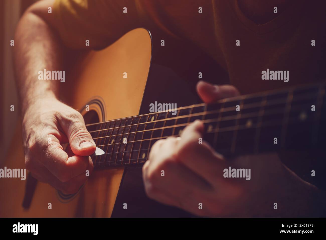 Mann, der zu Hause Akustikgitarre spielt, leises Bild mit selektivem Fokus Stockfoto