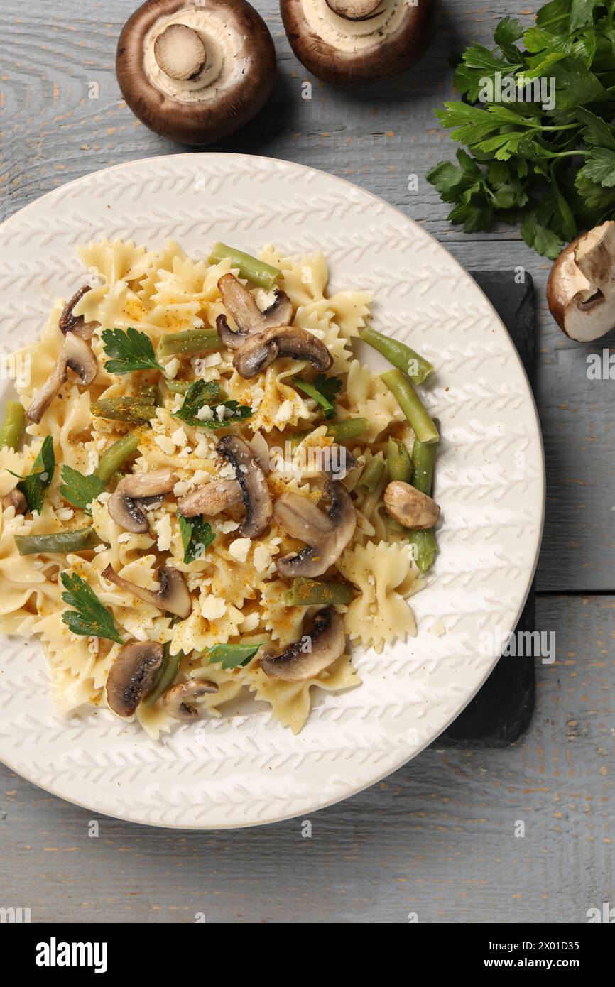 Vegetarische Pasta mit Pilzen, Petersilie, Bohnen und Käse auf grauem Holztisch, Blick von oben Stockfoto