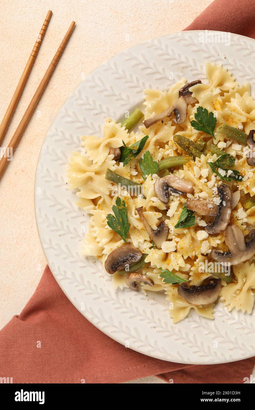 Vegetarische Pasta mit Pilzen, Petersilie, Bohnen und Käse auf orangefarbenem Tisch, Blick von oben Stockfoto