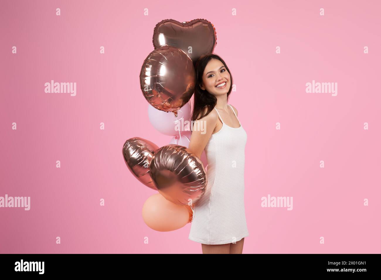 Fröhliche Dame mit Herzballons auf rosa Hintergrund Stockfoto