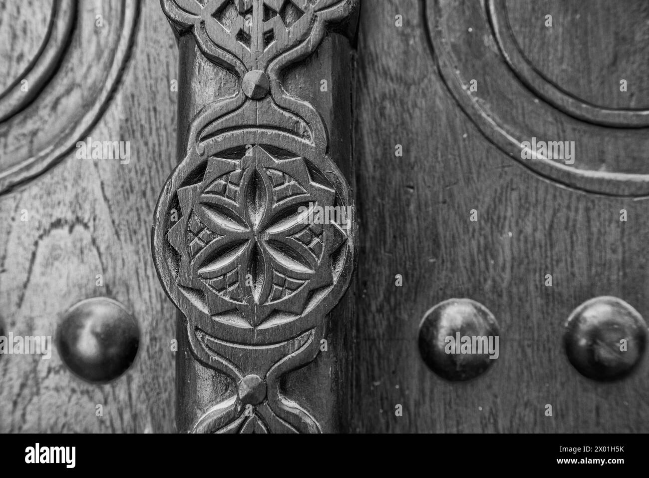 Einfarbige, gefilterte Details einer geschnitzten Holztür am Eingang zu einem restaurierten traditionellen arabischen Haus. Stockfoto