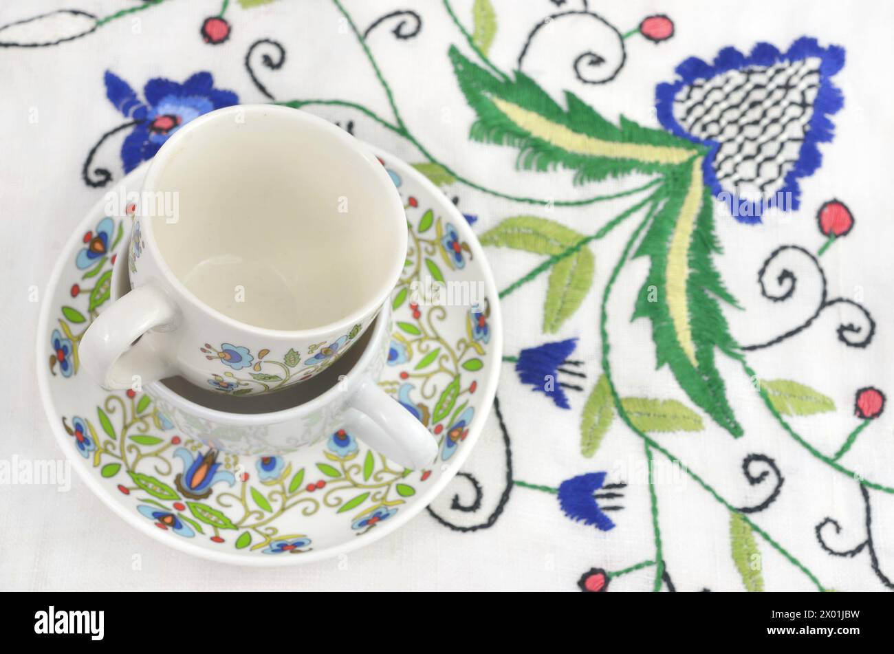 Zwei Tassen mit kaschubischen Mustern auf einer Tischdecke mit traditioneller Stickerei. Stockfoto