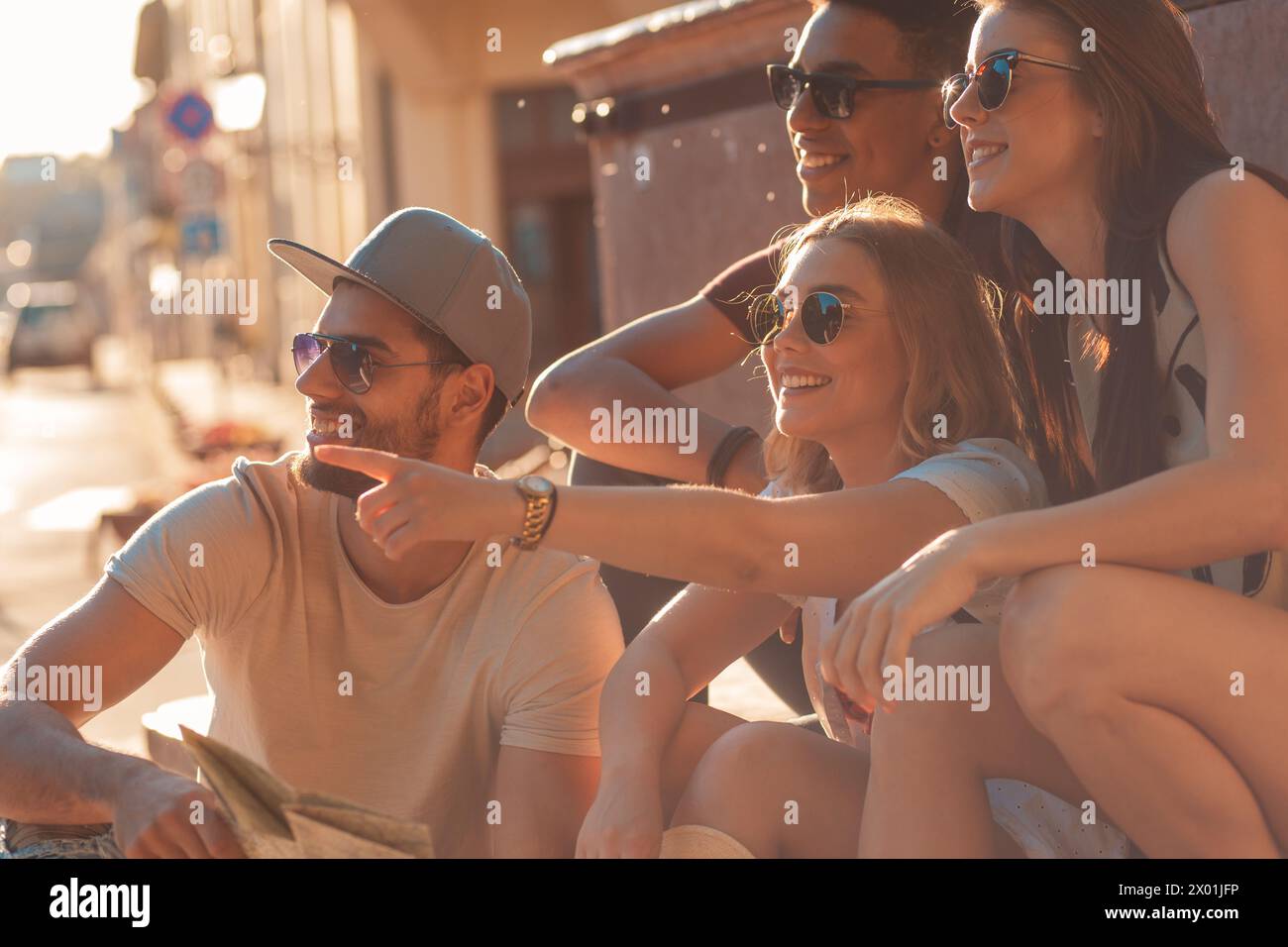 Gruppe von Freunden im Urlaub mit Karte, die am Marktplatz sitzt und viel Spaß hat. Stockfoto