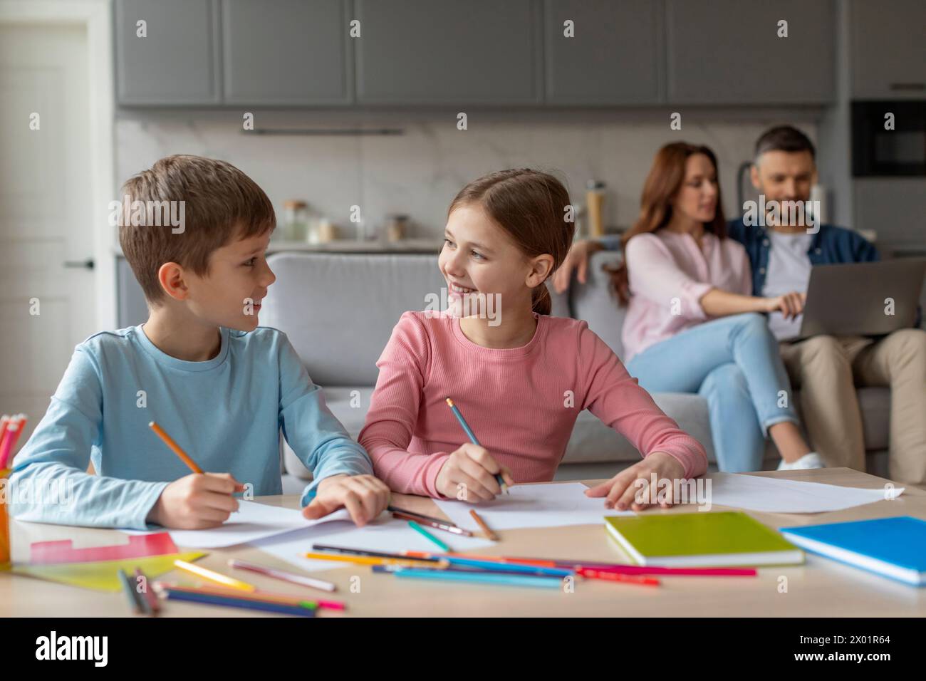 Kinder, die gemeinsam Hausaufgaben machen, Eltern mit Hintergrund Stockfoto