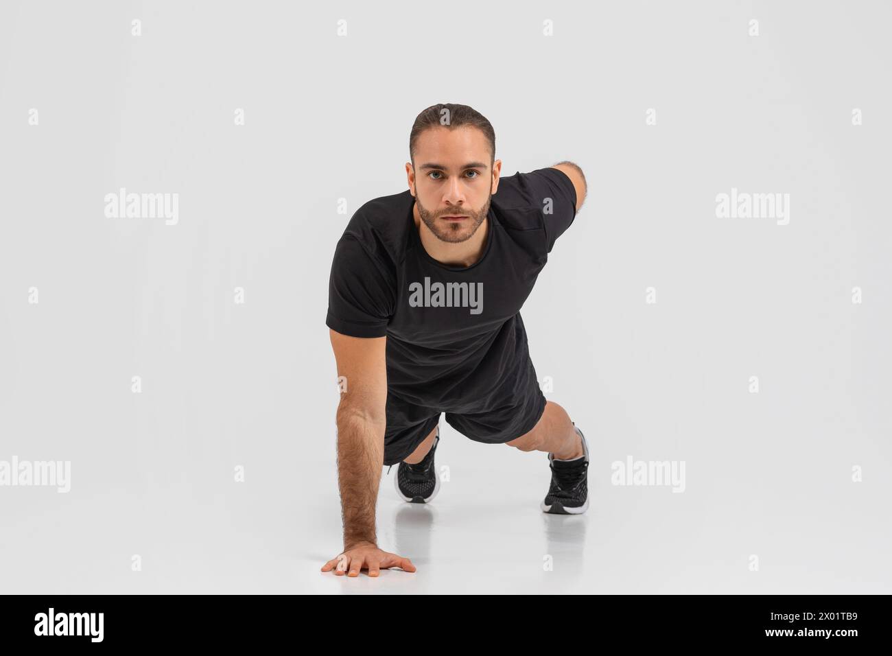 Mann in Schwarz, der Liegestütze auf grauem Hintergrund macht Stockfoto