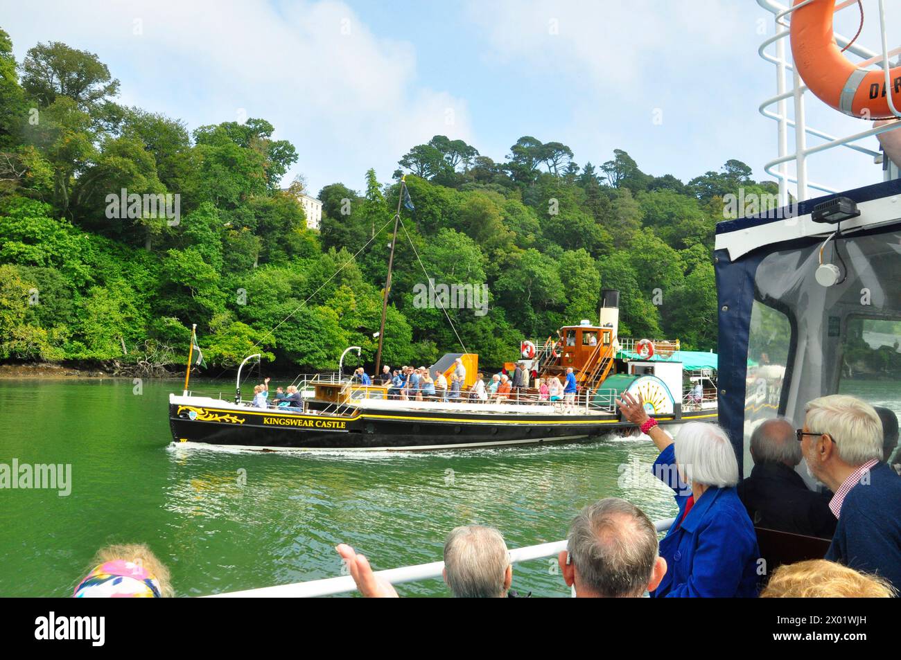 Passagiere auf einem Sportboot tauschen ihre Grüße aus, während der Raddampfer Kingswear Castle auf einem Brght su flussaufwärts von Dartmoth nach Totnes in Devon gleitet Stockfoto
