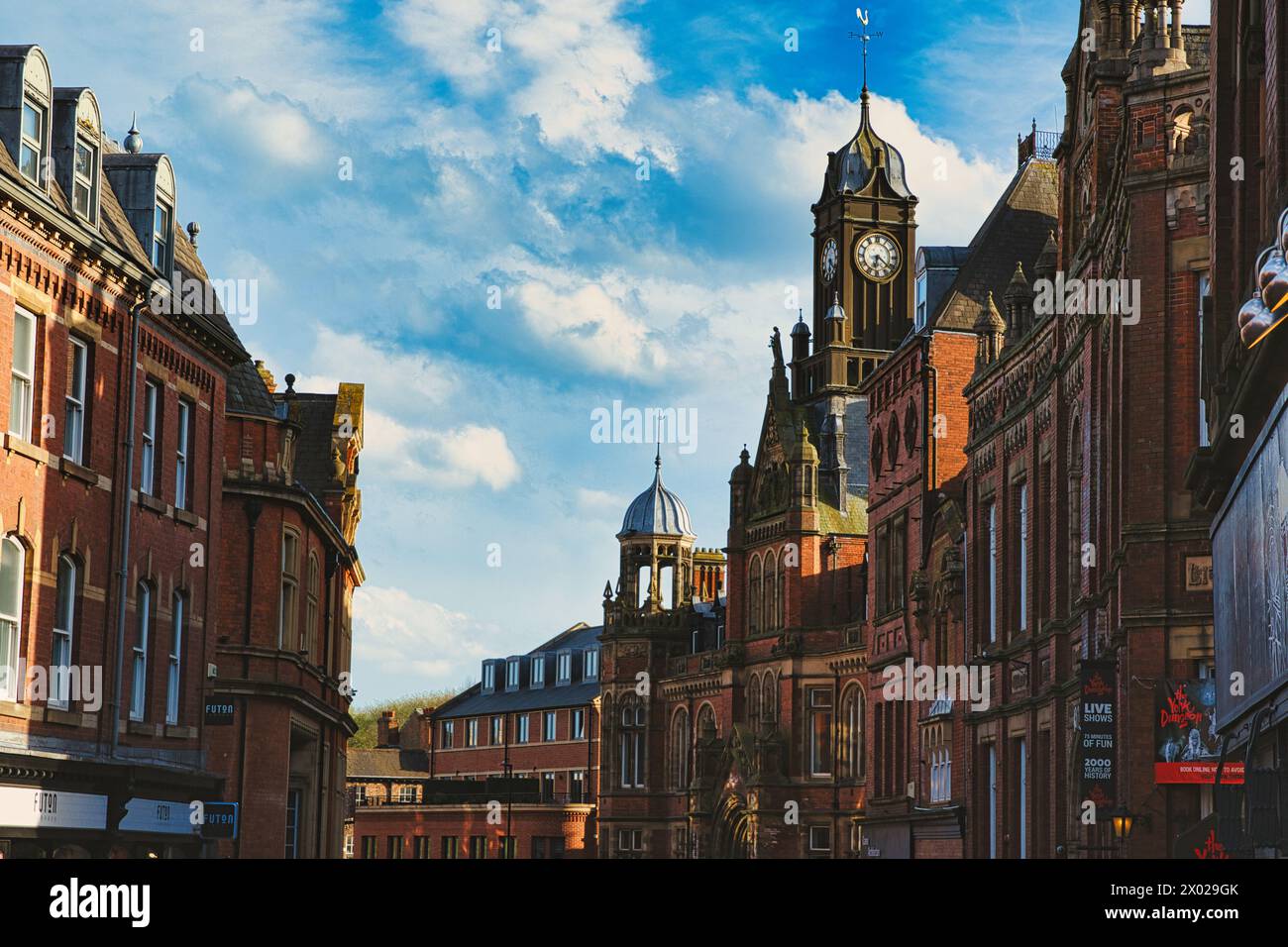 Historische europäische Architektur mit einem Uhrenturm unter blauem Himmel mit Wolken. Alte Gebäude mit komplizierten Details in einem Stadtbild in York, North Yor Stockfoto