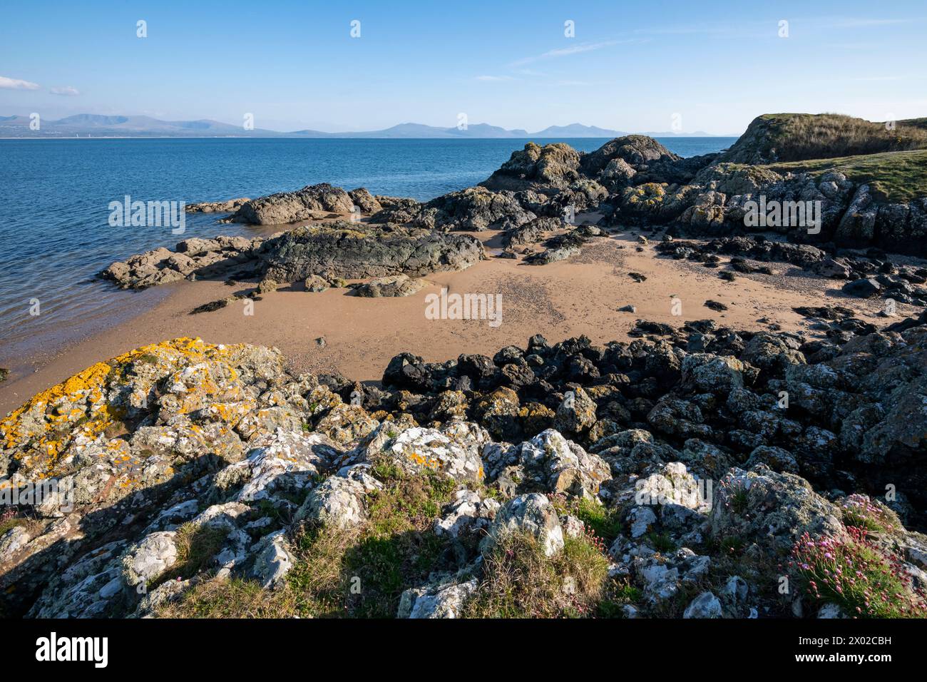 Wunderschöne Aussicht von Llanddwyn Island auf Anglesey mit den Bergen des walisischen Festlandes am Horizont. Stockfoto