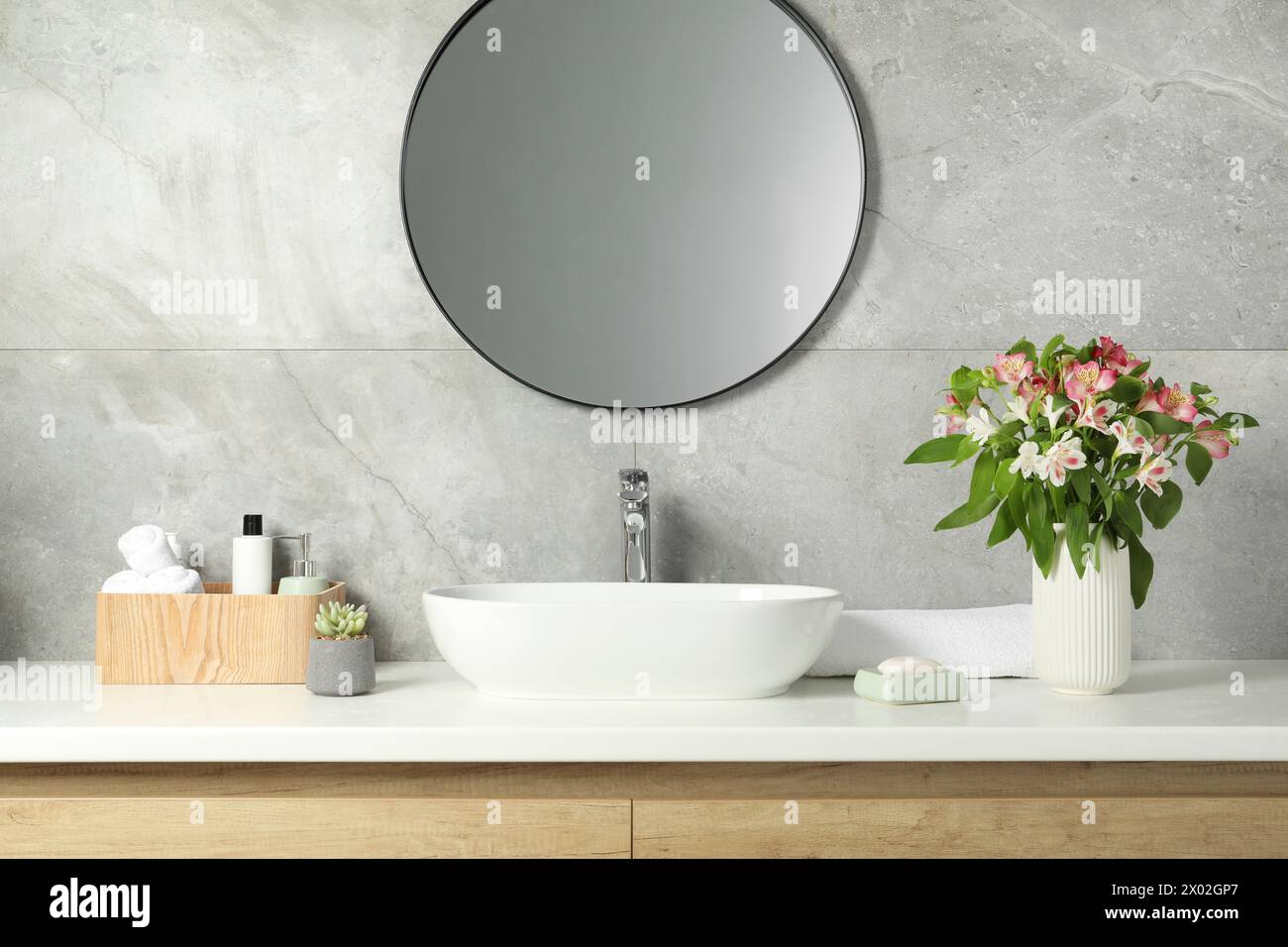 Vase mit wunderschönen Alstroemeria-Blumen und Toilettenartikeln in der Nähe des Waschbeckens im Badezimmer Stockfoto Vase mit wunderschönen Alstroemeria-Blumen und Toilettenartikeln in der Nähe des Waschbeckens im Badezimmer Stockfoto