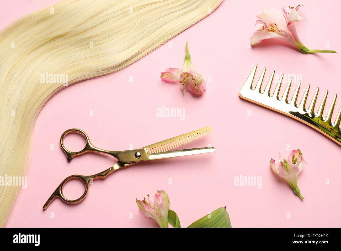Friseurwerkzeuge. Blondes Haarschloss, Kamm, Schere und Blumen auf rosa Hintergrund, flach Stockfoto