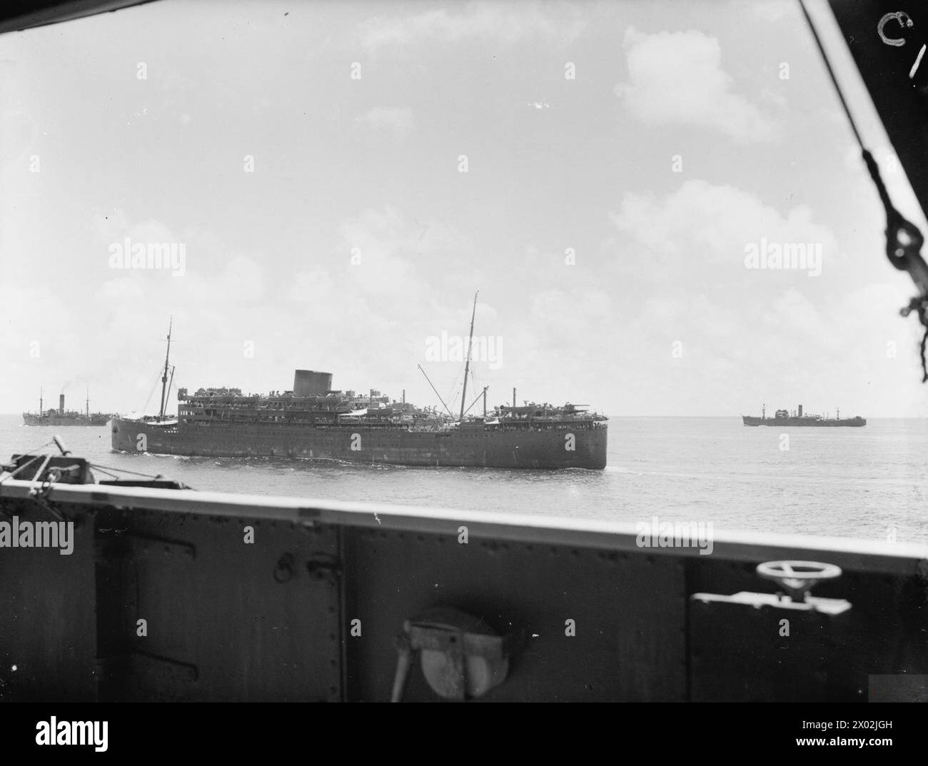 IM KONVOI VON BOMBAY NACH SINGAPUR. FEBRUAR 1942, AN BORD DES TRUPPENSCHIFFS DEVONSHIRE WÄHREND DER FAHRT VON BOMBAY NACH SINGAPUR UND BATAVIA (DJAKARTA) UND RÜCKKEHR, IN DEM WAHRSCHEINLICH LETZTEN KONVOI, DER SINGAPUR MIT TRUPPEN UND LAGERN ERREICHTE. ABGESEHEN VON EINEM LUFTANGRIFF JAPANISCHER FLUGZEUGE AUF DER FAHRT DURCH DIE BANGKA-STRASSE WAR DIE REISE EREIGNISLOS. - Konvoi fährt nach Batavia und Singapur. Die nächste Kamera ist SS WARWICK CASTLE mit Truppen an Bord Stockfoto