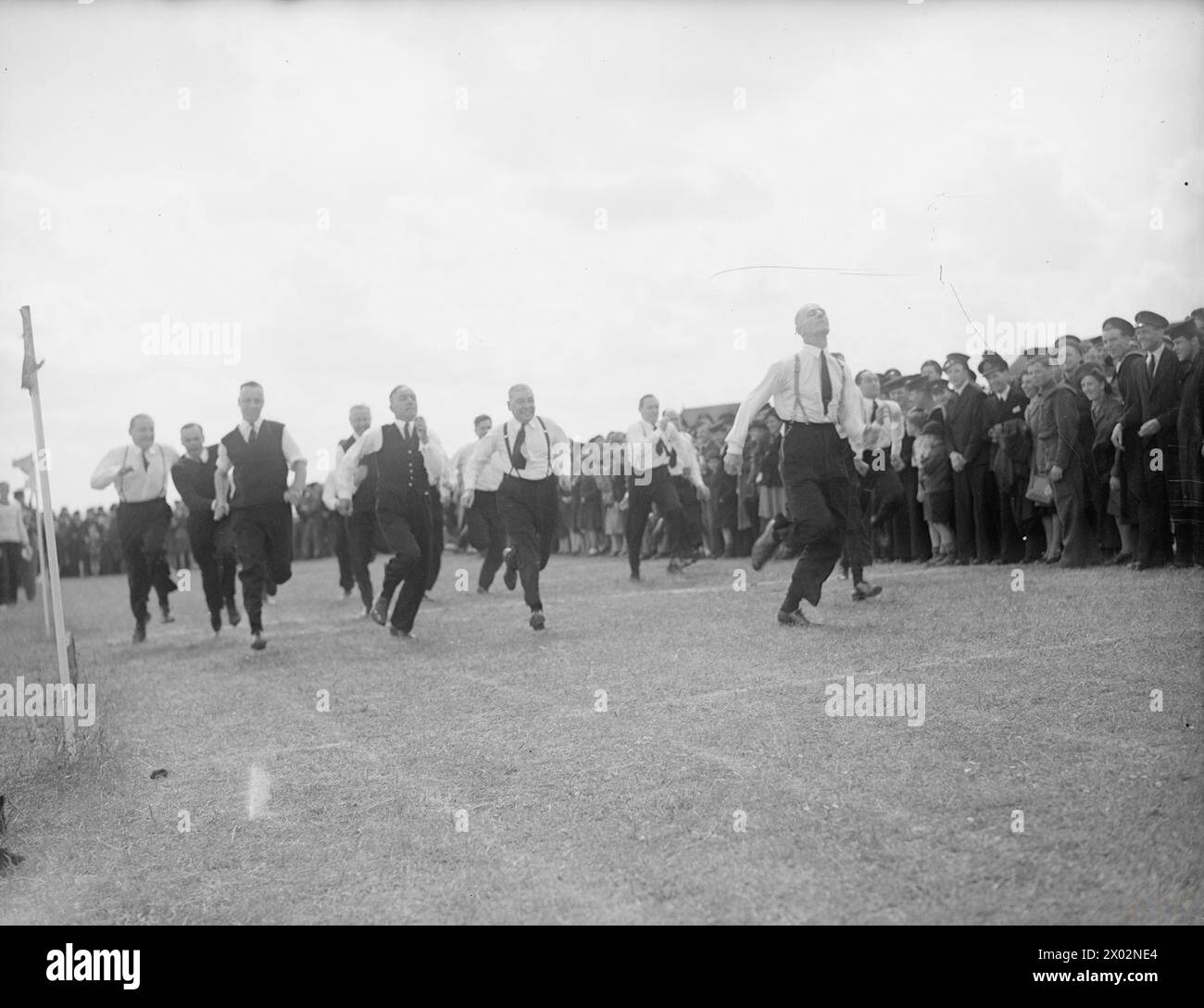 INBETRIEBNAHME DER MOBILEN MARINEFLUGSTATION. 1. JUNI 1945, ROYAL MARINEFLUGSTATION AM MITTLEREN WALLOP, HANTS. DER INBETRIEBNAHME- UND SPORTTAG DER HMS NABREEKIE, EINER MOBILEN MARINEFLUGSTATION, DIE FÜR DEN BETRIEB IM PAZIFIK BESTIMMT IST. DER DIENST WURDE VOM KAPLAN DER FLOTTE DURCHGEFÜHRT. - Das 100-Yard-Rennen der über 40 Senior Officers. Konteradmiral L D Mckintosh und Captain Frai, Kommandeur der HMS NABREEKIE, traten an Stockfoto