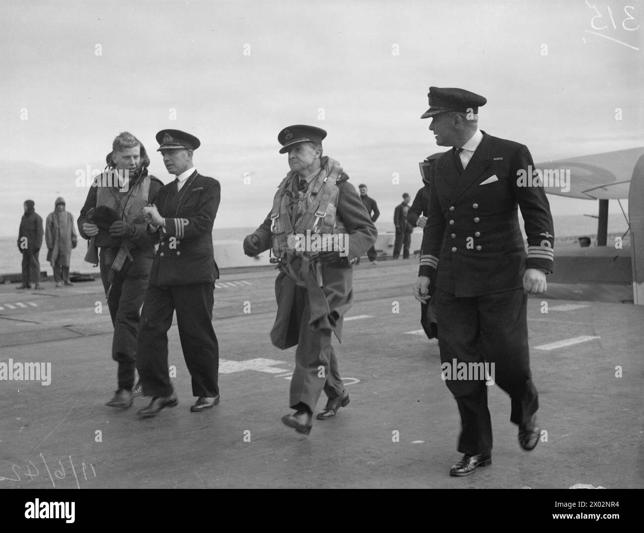 RAF-OFFIZIERE BESUCHEN FLUGZEUGTRÄGER DER HEIMATFLOTTE. - L bis R: Commander V N Surtees, DSO, RN, Air Commander B E Baker, DSO, MC, AFC und Commander H S Ronald, OBE, RN auf dem Cockpit Stockfoto