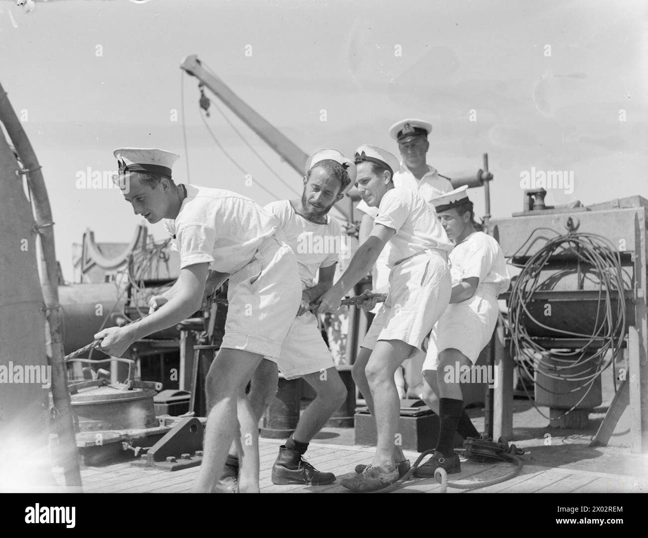 DIE MEERE WIEDER SICHER MACHEN. 1945. AUGUST AUF SEE IM GOLF VON GENUA. MIT DER 12. MINENRÄUMUNGSFLOTTE IM GOLF VON GENUA UNTER DEM KOMMANDO VON COMMANDER C SIMPSON, DSC, RN, COMMANDER MINENRÄUMUNG WESTITALIENS. SIE ARBEITEN AUF DER GRUNDLAGE VON KAPITULIERTEN FEINDKARTEN UND WERDEN VON SUPERMARINE WALROSSEFLUGZEUGEN UND DER US NAVY-ABSCHOTTUNG ZUR MINENBEOBACHTUNG UNTERSTÜTZT. - An Bord der HMS CIRCE. Biegen in einen neuen Schneidedraht. Von links nach rechts: Able Seaman B F Smith of Gloucester; Able Seaman R W Lunn of Watford; Able Seaman K A Eldrett of Enfield; Leading Seaman J Fitzpatrick of Wigan; Lieut A J Beavis, RNVR, o Stockfoto