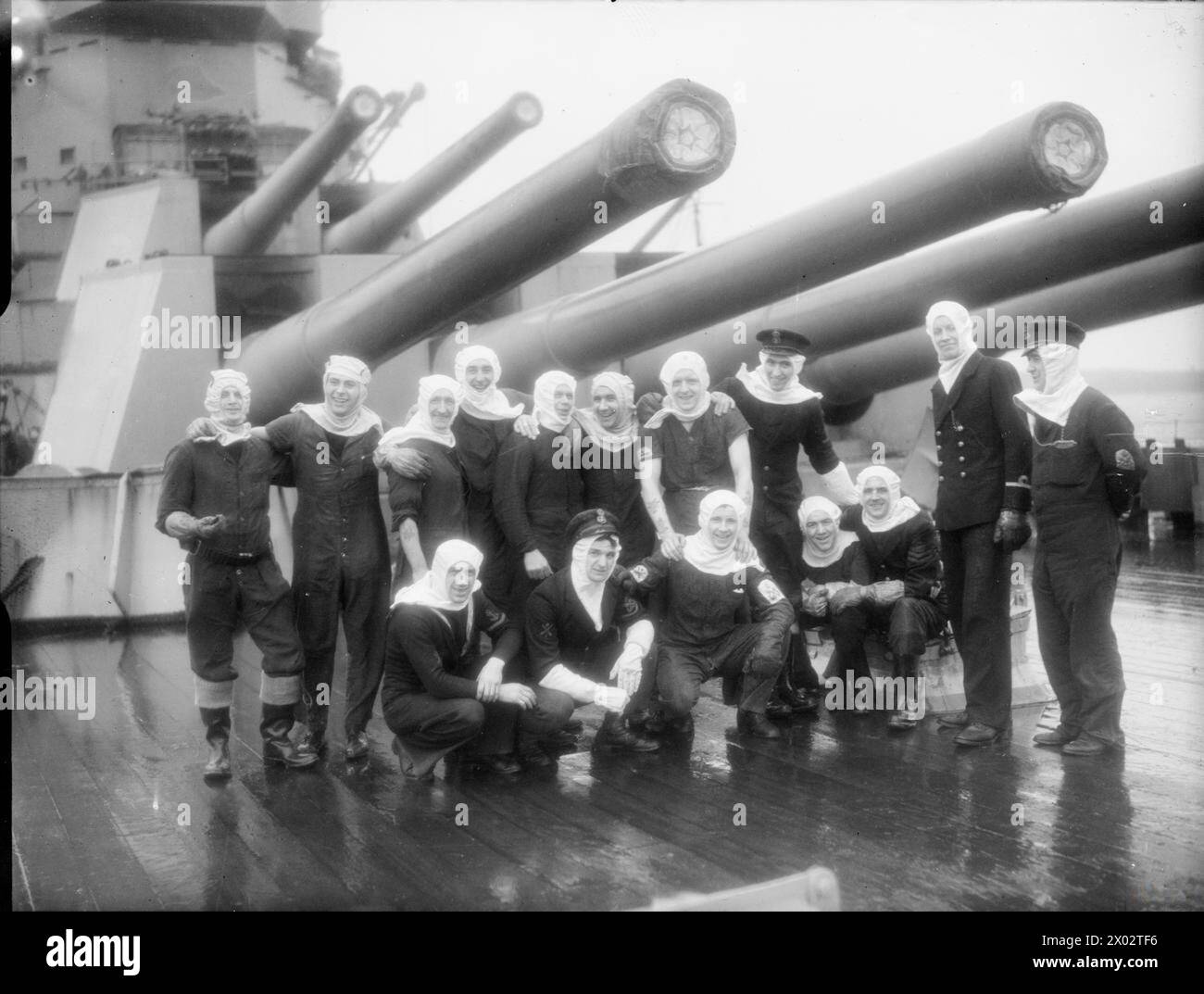 Geschützbesatzungen der HMS Duke of York sind unter den 14-Zoll-Geschützen des Schiffs Scapa Flow nach dem Untergang des deutschen Kriegsschiffs Scharnhorst am 26. Dezember 1943 zu sehen. Der Sub-Lieutenant auf der rechten Seite ist wahrscheinlich Henry Leach. Stockfoto Geschützbesatzungen der HMS Duke of York sind unter den 14-Zoll-Geschützen des Schiffs Scapa Flow nach dem Untergang des deutschen Kriegsschiffs Scharnhorst am 26. Dezember 1943 zu sehen. Der Sub-Lieutenant auf der rechten Seite ist wahrscheinlich Henry Leach. Stockfoto
