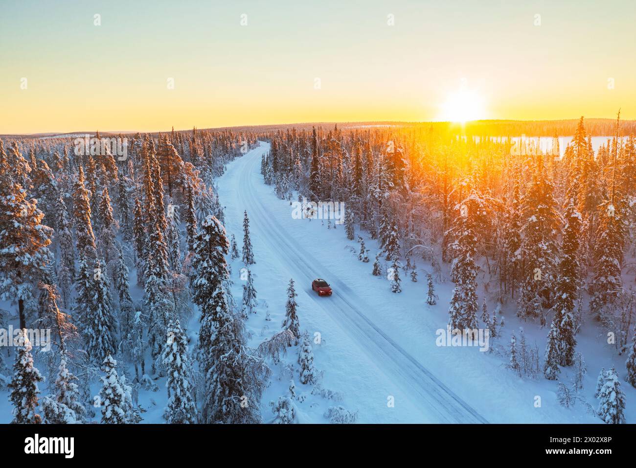 Das Auto fährt die eisige und leere Straße durch den schneebedeckten Wald bei Sonnenaufgang, Schwedisch Lappland, Schweden, Skandinavien, Europa Stockfoto