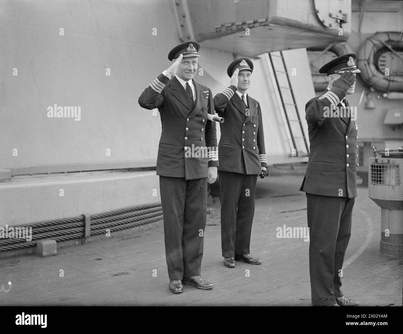 ADMIRAL I G GLENNIE NEUE RAD-HEIMFLOTTE BESUCHT C-IN-C-HEIMFLOTTE. 13. JANUAR 1943, SCAPA FLOW. - Offiziere des Flaggschiffs der Heimatflotte, HMS KING GEORGE V., grüßen als Konteradmiral I G Glennie, kommandierende Zerstörer der Heimatflotte, verlassen das Schiff, nachdem sie die C-in-C angerufen haben Von links nach rechts; Kapitän P J Mack, DSC, RN; Kapitän A E M B Cunningham-Grahm, RN; Kommandant E F H C Rutherford, RN Stockfoto