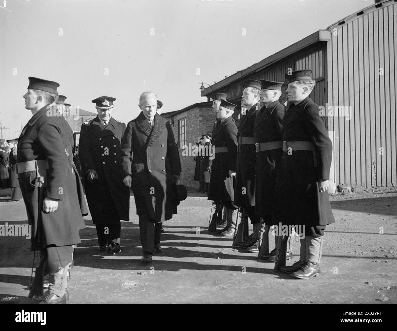 DIE ERSTEN VOLLSTÄNDIG DÄNISCHEN KAMPFSCHIFFE, DIE MIT DEN VERBÜNDETEN DIENEN. 1. MÄRZ 1944, GRANTON. ZWEI MOTOR-MINEWSWEEPERS, DIE ERSTEN KAMPFSCHIFFE, DIE IM KRIEG GEGEN DEUTSCHLAND VON DÄNEN BEMANNT WURDEN, WURDEN BEI EINER ZEREMONIE AM UFER IN ANWESENHEIT DES DÄNISCHEN MINISTERS GRAF REVENTLOW AN IHRE DÄNISCHEN BESATZUNGEN ÜBERGEBEN. - Graf Reventlow inspiziert die Ehrengarde Stockfoto