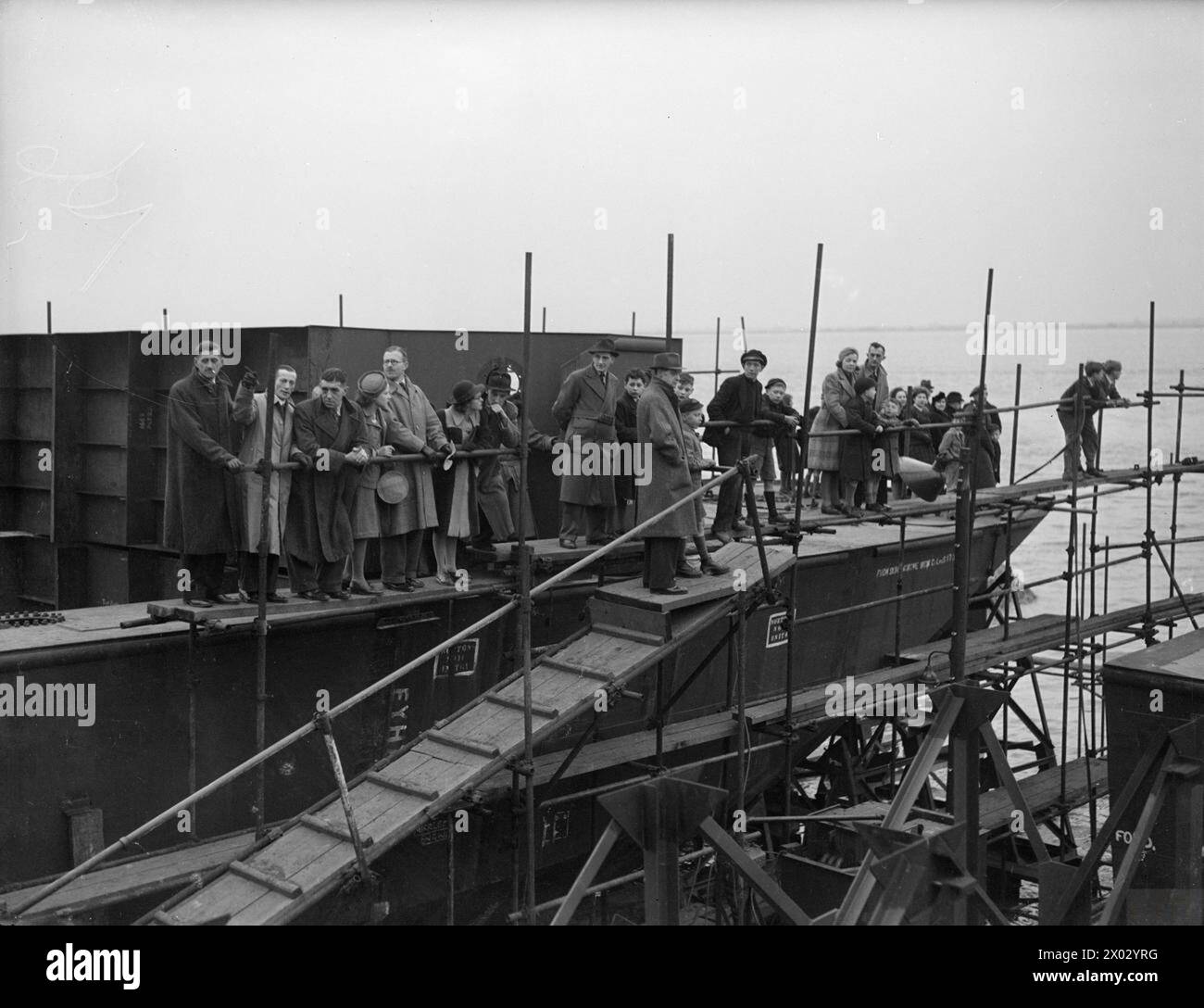 MÄNNER UND FRAUEN, DIE GROSSBRITANNIENS FABRIZIERTE SCHIFFE BAUEN. APRIL 1944, DIE BRITISCHEN WERFTEN DER HENRY SCARR LTD, HESSLE NAHE HULL. - Männer und Frauen, die beim Bau des Schiffes geholfen haben, den Start von der Wiege um das nächste Schiff, das gebaut wird, zu beobachten Henry Scarr Ltd Stockfoto