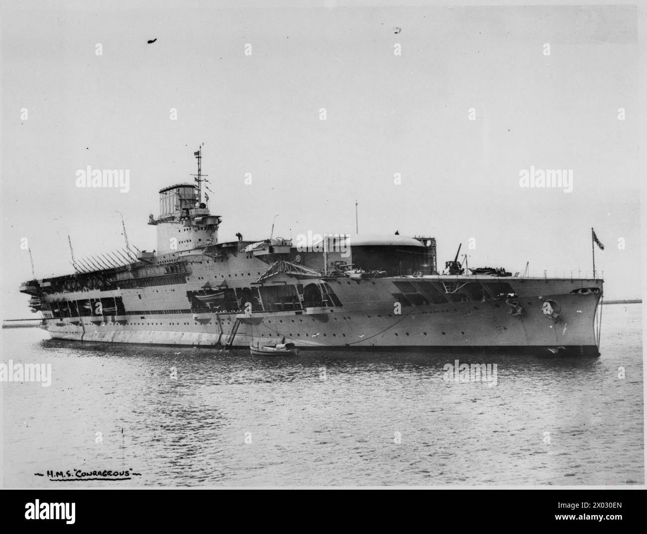 HMS mutig stationär in Küstengewässern, zeigt den Flugzeugträger in Ruhe mit der Besatzung, die Routinearbeiten durchführt. Stockfoto