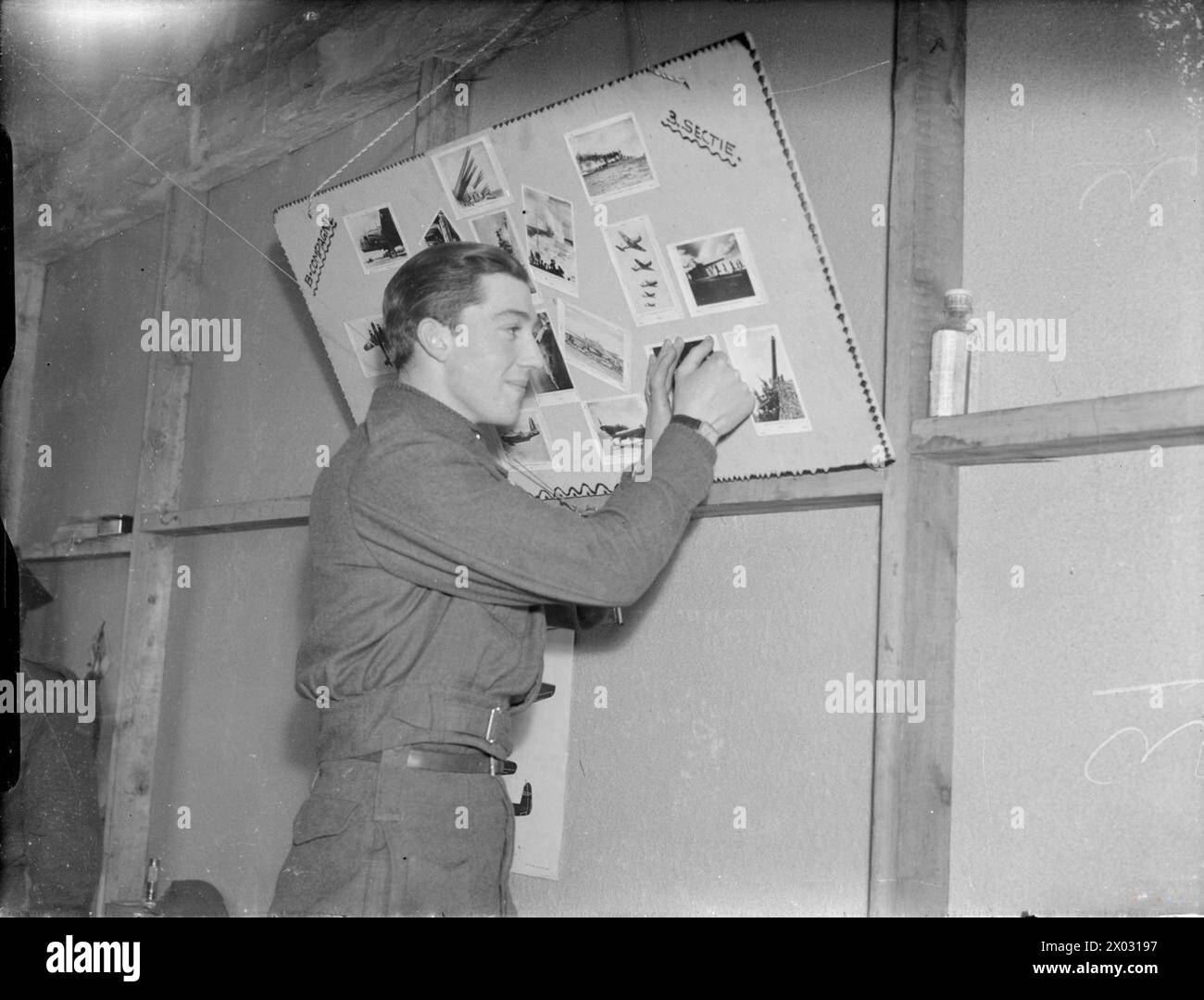 NIEDERLÄNDISCHE TRUPPEN TRAINIEREN IN ENGLAND, 1941 - Ein Soldat pinnt ein weiteres Foto in die Bildergalerie verschiedener Waffen auf einer Pinnwand in der Kaserne von „B Companie 3 Sectie“, irgendwo in England im Jahr 1941 Stockfoto