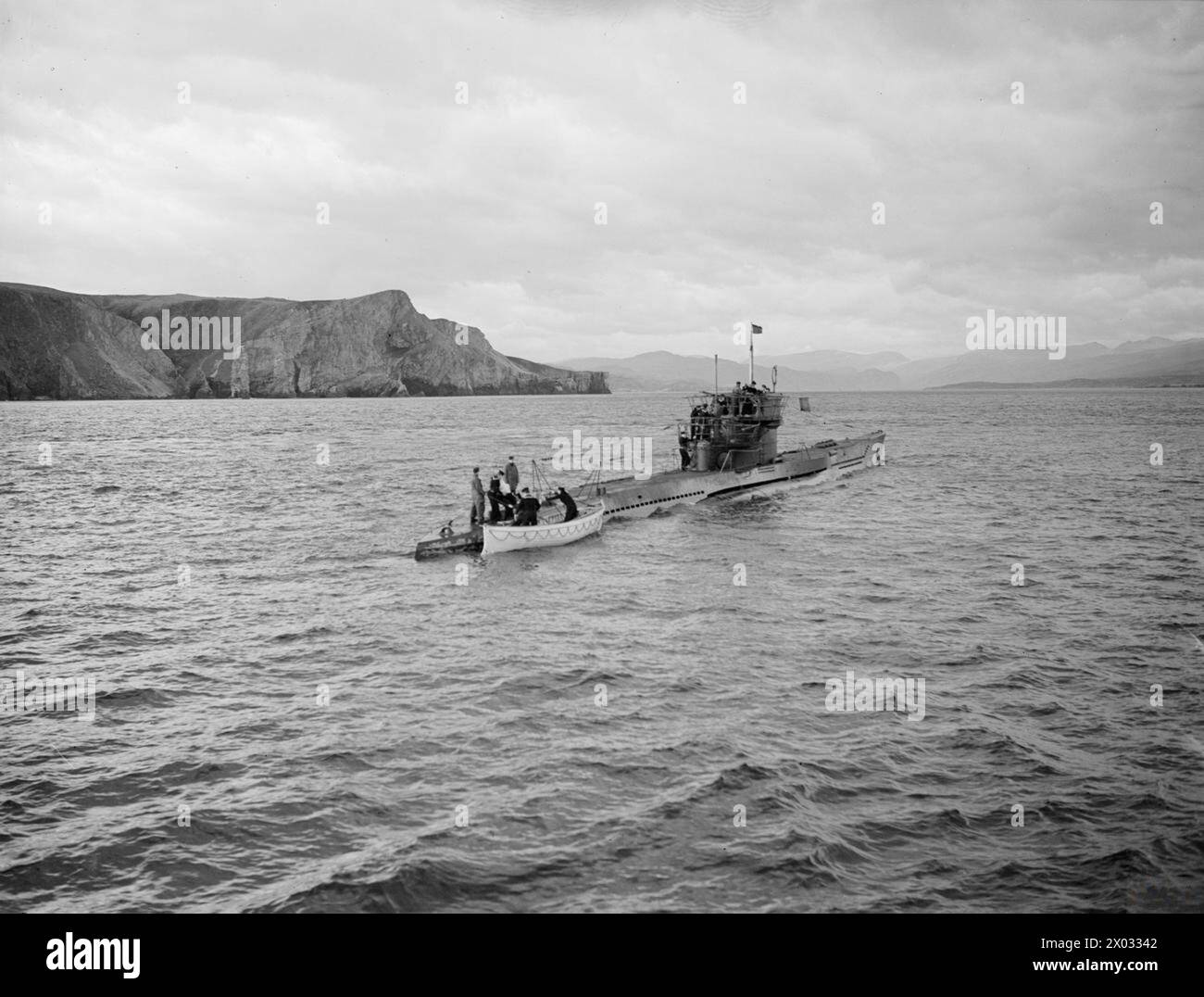 U-BOOTE ERGEBEN SICH AM LOCH ERIBOLL. 9. UND 10. MAI 1945, LOCH ERIBOLL, SCHOTTLAND. DIE ERSTE DEUTSCHE U-BOOT-FLOTTE BEGANN IHRE KAPITULATION VOR DEN TRUPPEN DER ROYAL NAVY. - Eine britische bewaffnete Wache geht an Bord von U-Boot 1305 zur Inspektion U 1305 Stockfoto