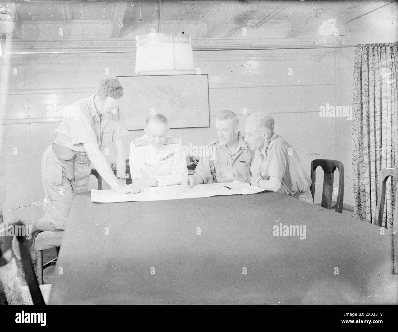 Am 7. Mai 1942 veranstaltet die HMS Ramillies eine Konferenz nach der Kapitulation Frankreichs in Diego Suarez, bei der britische Offiziere die Schlachtkarte studieren. Stockfoto