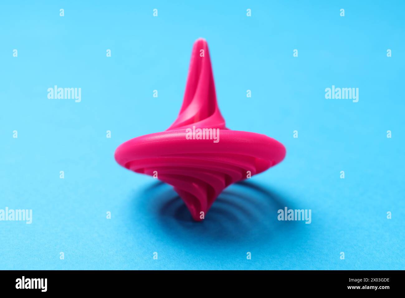 Ein rosafarbenes Spinntop auf hellblauem Hintergrund, Nahaufnahme Stockfoto