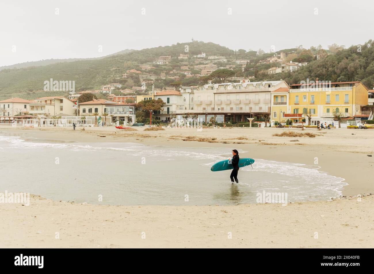 Eine Frau übt Surfen im rauen Meer vor der Küste von Castiglion della Pescaia in der Toskana (Italien) Stockfoto
