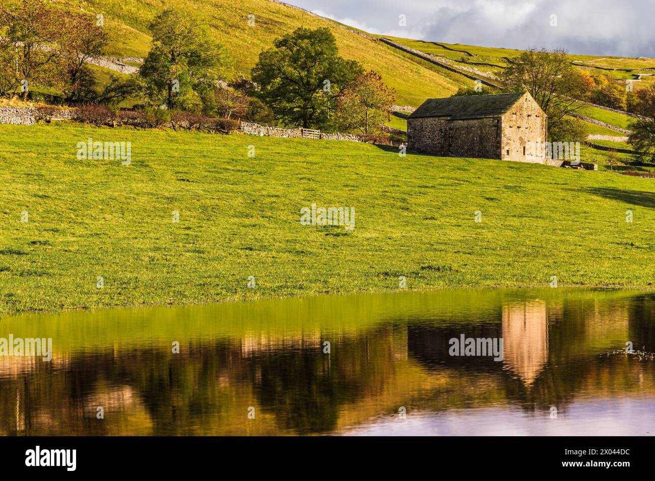 Traditionelle Steinscheune spiegelt sich in einem überfluteten Feld in der Nähe von Kettlewell, Wharfedale, Yorkshire Dales, England. Stockfoto