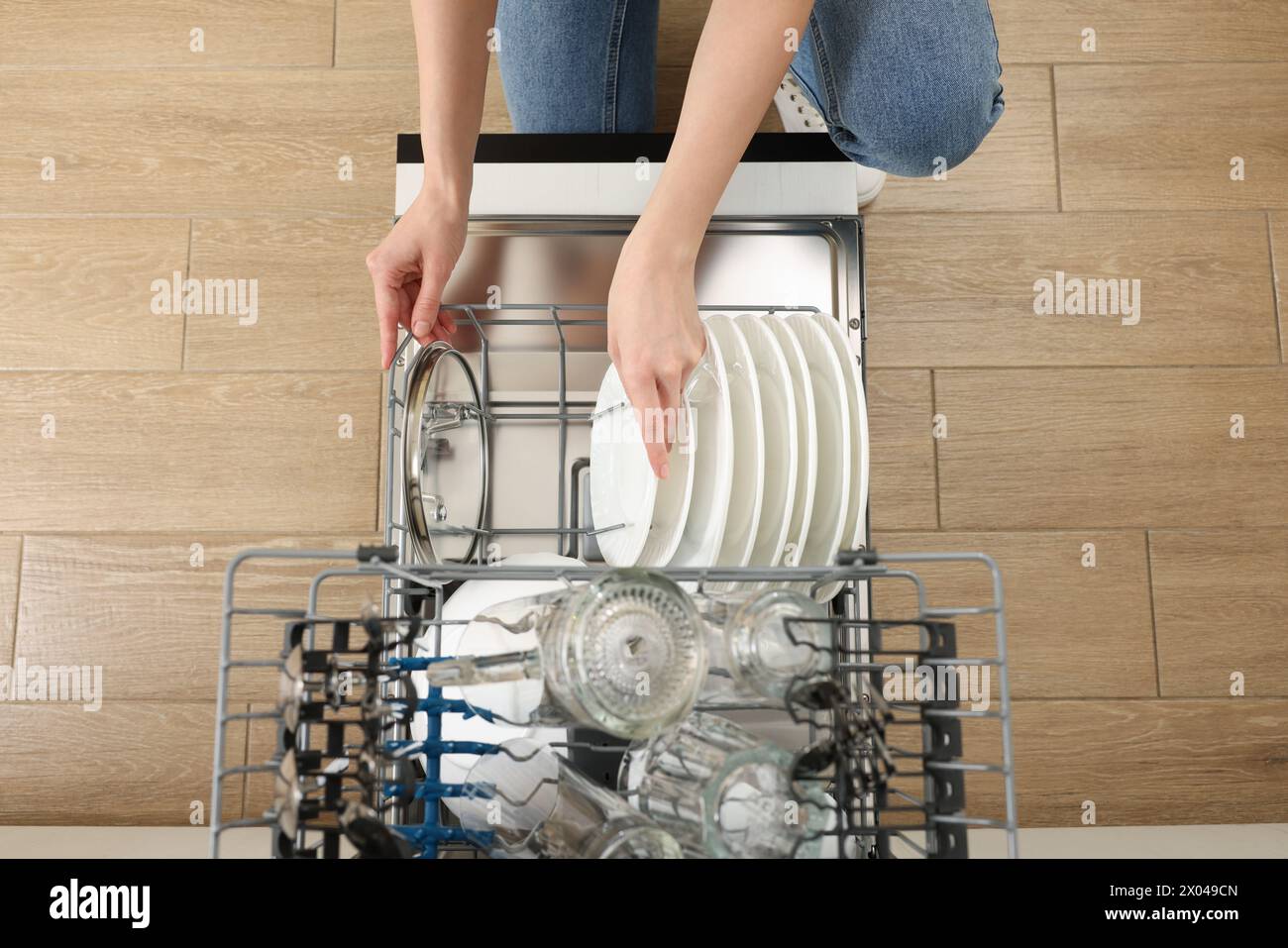 Frau, die Geschirrspüler mit Gläsern und Tellern lädt, Blick von oben Stockfoto